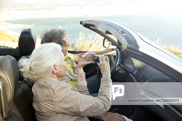 South Africa  senior couple sitting in a convertible looking at view