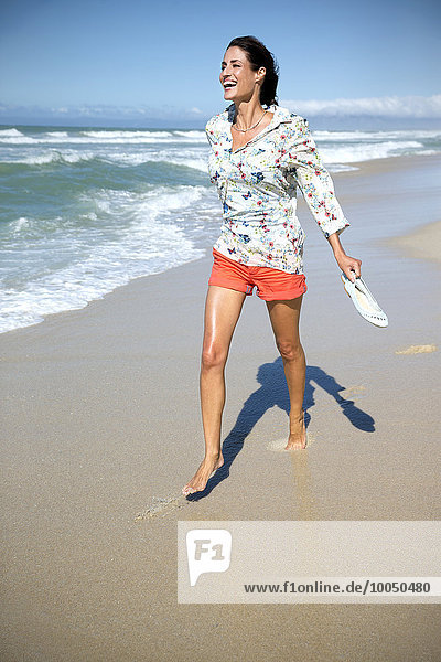 Südafrika  lachende Frau  die am Strand spazieren geht.