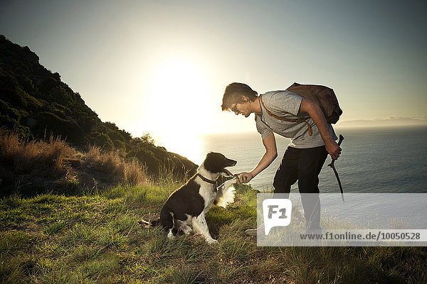 Südafrika  Mann mit Hund an der Küste bei Sonnenuntergang