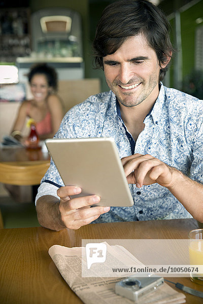 Porträt eines lächelnden Mannes mit digitalem Tablett im Cafe