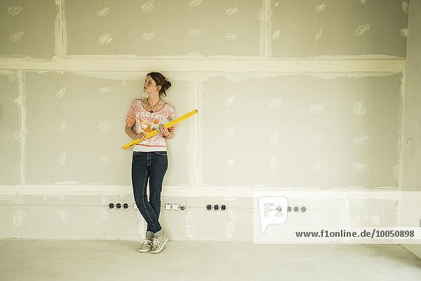Young woman renovating standing at blank wall