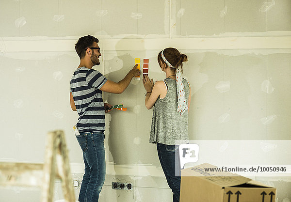 Couple holding colour samples at blank wall