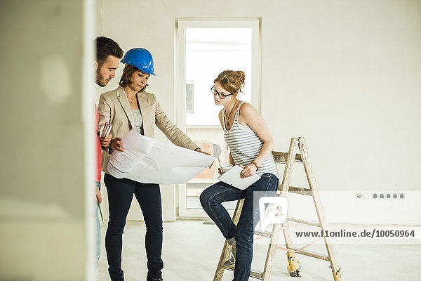 Architect showing construction plan to young couple