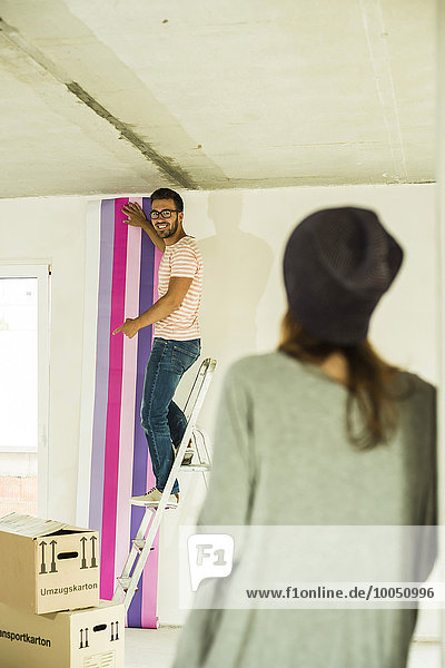 Young man renovating showing wallpaper to woman