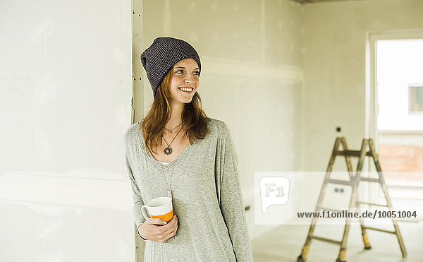 Lächelnde junge Frau bei einer Kaffeepause nach der Renovierung