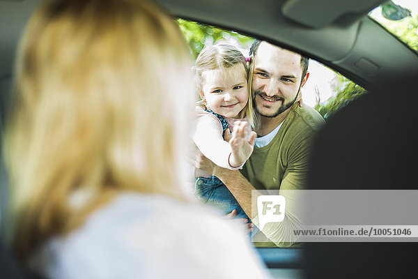 Mädchen mit Vater verabschiedet sich von der Mutter im Auto