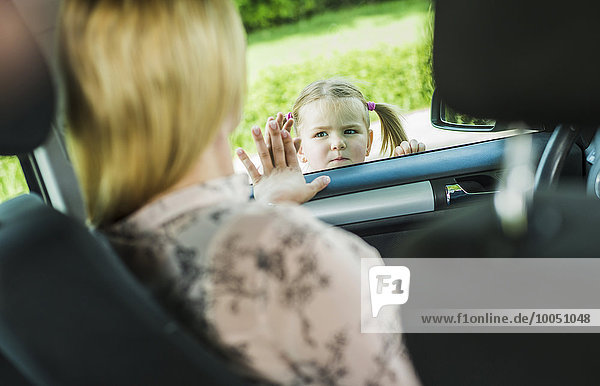 Mädchen verabschiedet sich von der Mutter im Auto