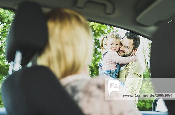 Mädchen mit Vater schaut Mutter im Auto an