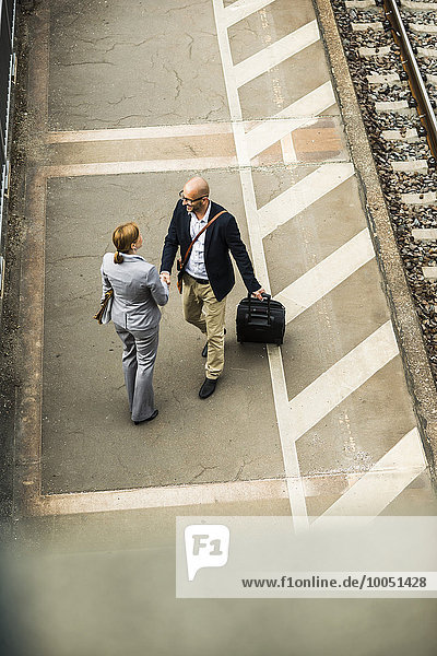 Businessman and businesswoman shaking hands on railway platform