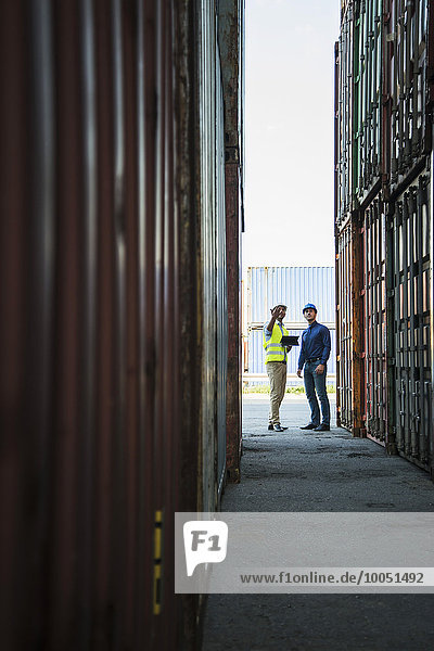 Zwei Männer mit Schutzhelmen im Containerhafen im Gespräch