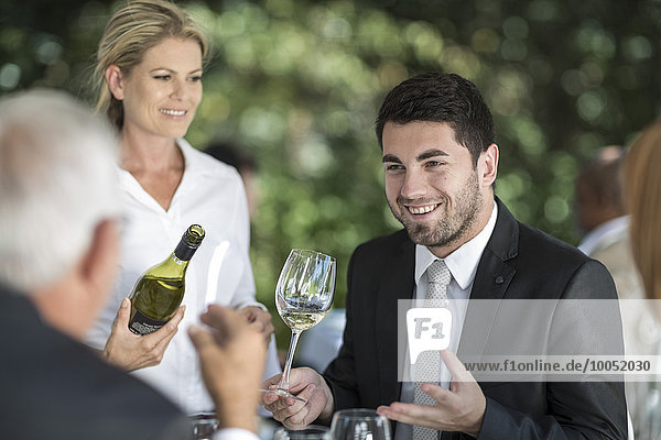 Kellnerin und Kundin mit einem Glas Weißwein