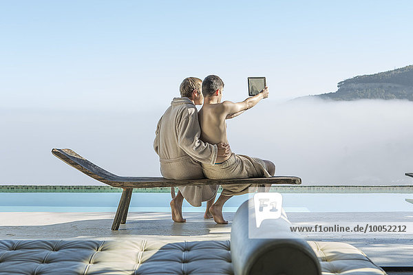 Schwules Paar am Pool mit einem Selfie mit digitalem Tablett