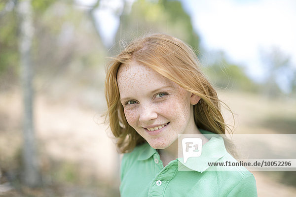 Porträt eines lächelnden Mädchens mit roten Haaren und Sommersprossen