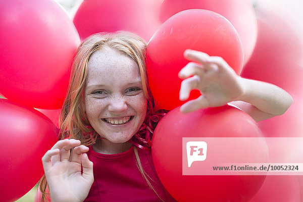 Portrait of smiling girl with red balloons