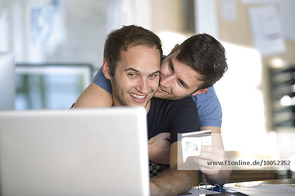 Happy gay couple with laptop shopping online