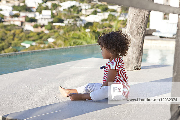 Little girl with curly hair sitting on terrace