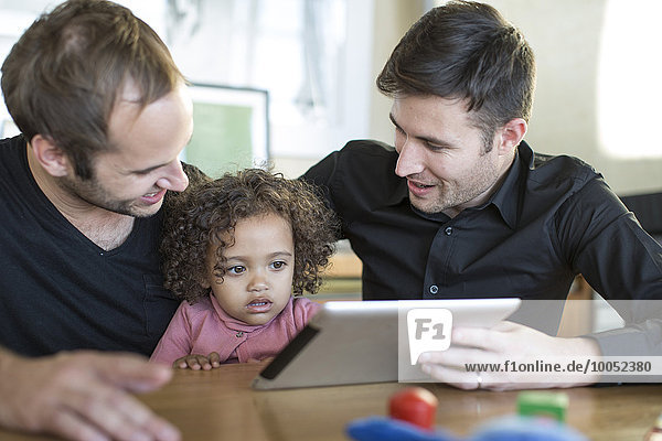 Zwei Männer mit Kind beim Betrachten des digitalen Tabletts