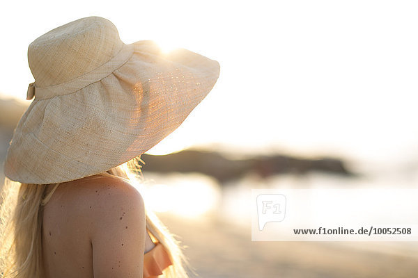 Junge Frau mit Sommerhut am Strand