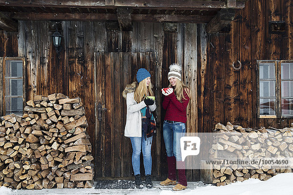 Zwei junge Freundinnen beim Plaudern vor der Holzhütte