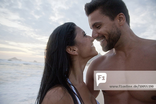 Mittleres erwachsenes Paar am Strand stehend,  von Angesicht zu Angesicht,  Nase berührend