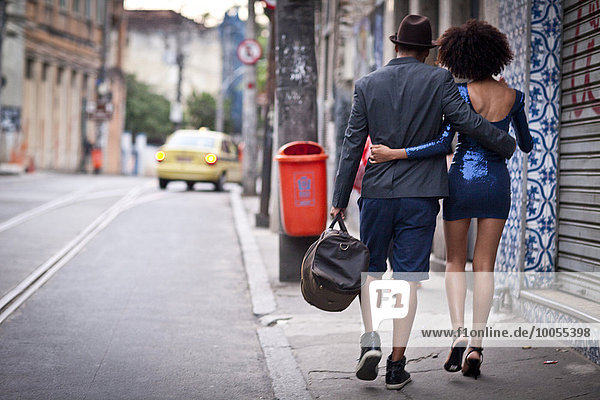 Couple walking along street together  rear view