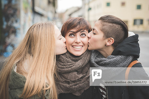 Sisters kissing woman on street