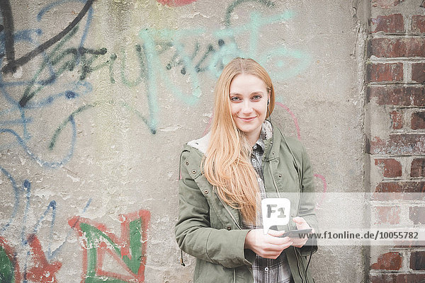 Junge Frau nutzt Smartphone von Graffiti Wall