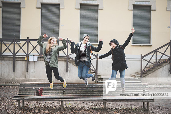 Drei Schwestern springen auf Parkbank