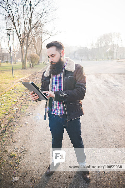 Junge bärtiger Mann mit digitalen Tablette im Park