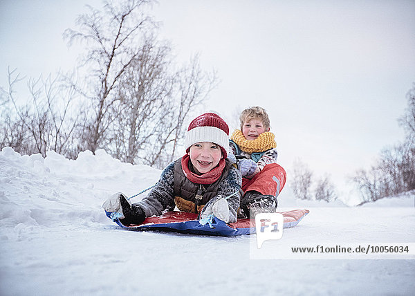 Low angle view of two brothers on toboggan on snow covered hill  Hemavan Sweden