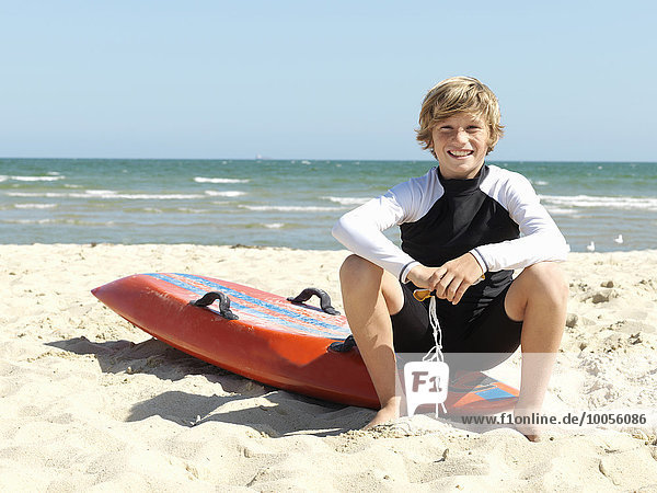 Portrait of confident boy nipper (child surf life savers) sitting on surfboard at beach  Altona  Melbourne  Australia