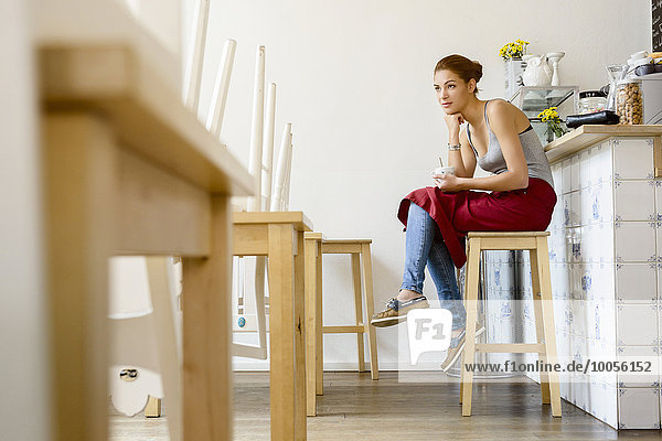 Waitress in cafe sitting on stool