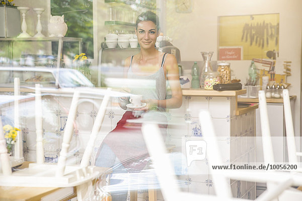 Young waitress sitting in cafe  view through window