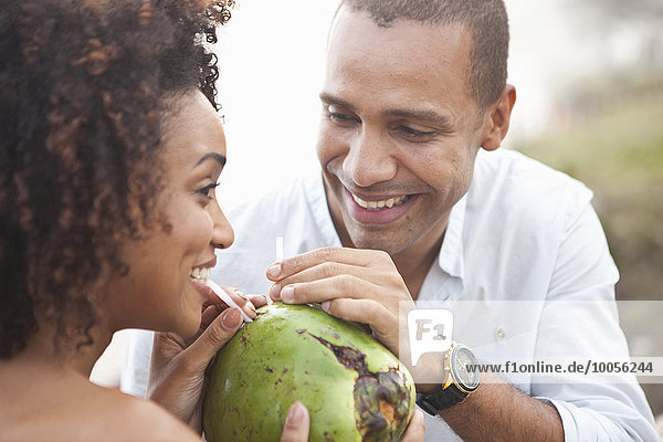 Nahaufnahme eines Paares  das sich Kokosmilch am Strand teilt  Rio De Janeiro  Brasilien