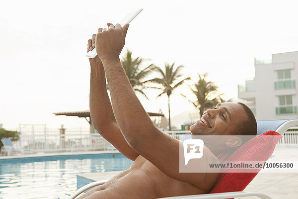 Mittlerer erwachsener Mann  der am Pool des Hotels in Rio De Janeiro  Brasilien  digitale Tabletten einnimmt