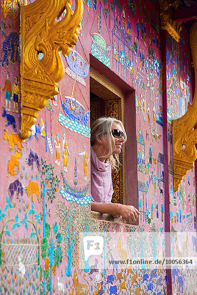 Female tourist looking out of Wat Xieng Thong window  Luang Prabang  Laos