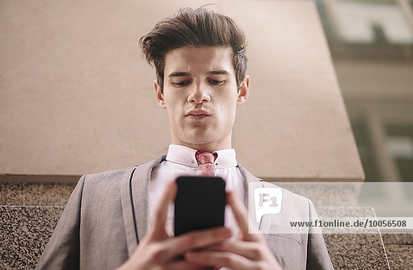 Low-Winkel-Ansicht der jungen Stadt Geschäftsmann Lesung Smartphone Text