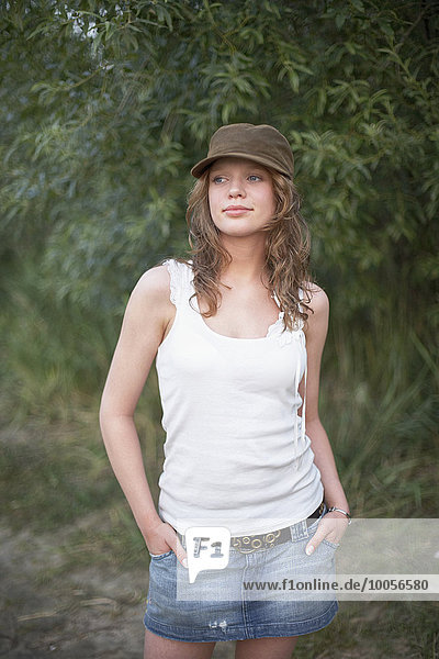 Portrait of young woman wearing cap with hands in pockets