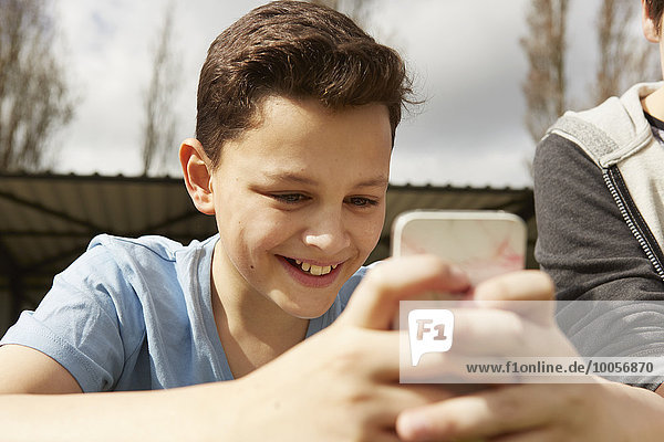 Lächelnder Junge liest Smartphone-Textnachricht