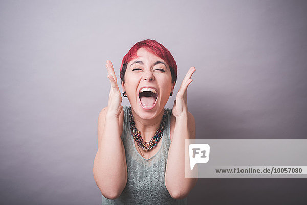 Studio-Porträt einer jungen Frau mit kurzen rosa Haaren  die lacht