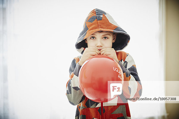Kleiner Junge bläst roten Ballon
