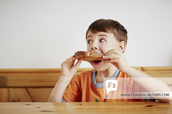 Junge isst ein Stück Toast.