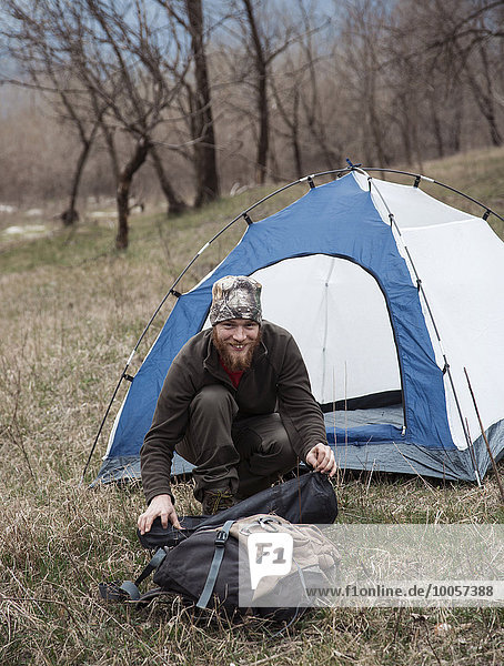 Mid adult man by tent smiling towards camera