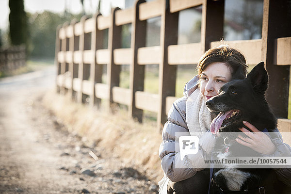 Portrait of mid adult woman with her dog on country lane