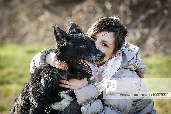 Portrait of mid adult woman kissing her dog in field