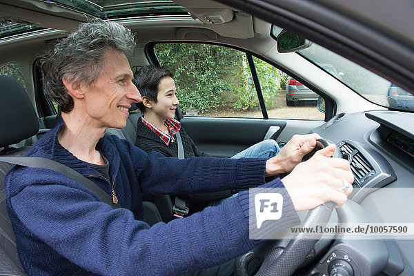 Mature man driving car with teenage son