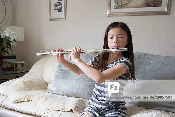 Girl playing the flute on sofa