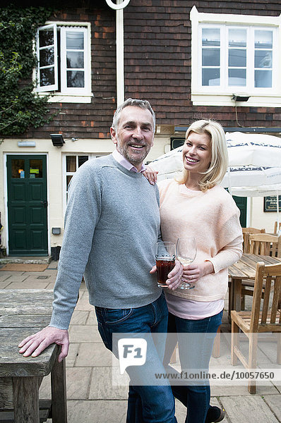 Portrait of couple with drinks in front of pub