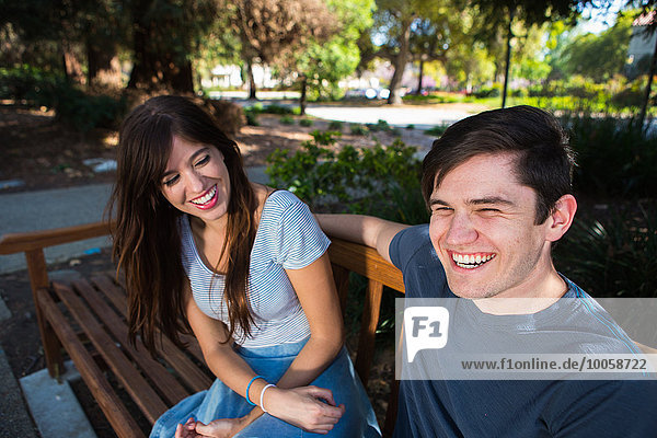 Young couple laughing on park bench
