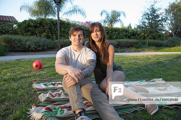 Portrait of young couple on picnic blanket in park